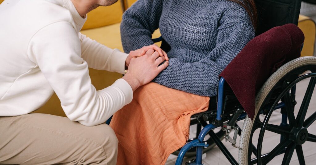 woman on a wheelchair with a man holding her hands